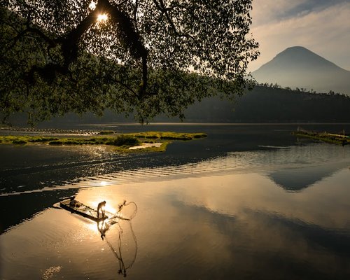 A seasoned Filipino fisherman casting his net at dawn, silhouette against the rising sun.